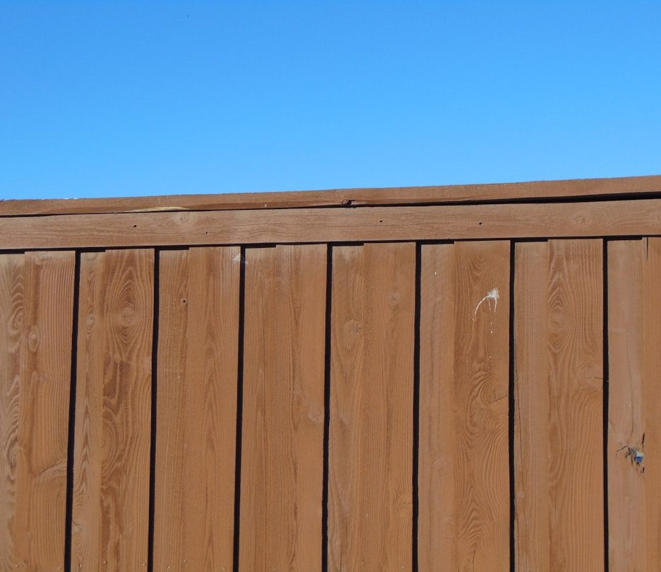 Close-up view of a wooden privacy fence against a blue sky